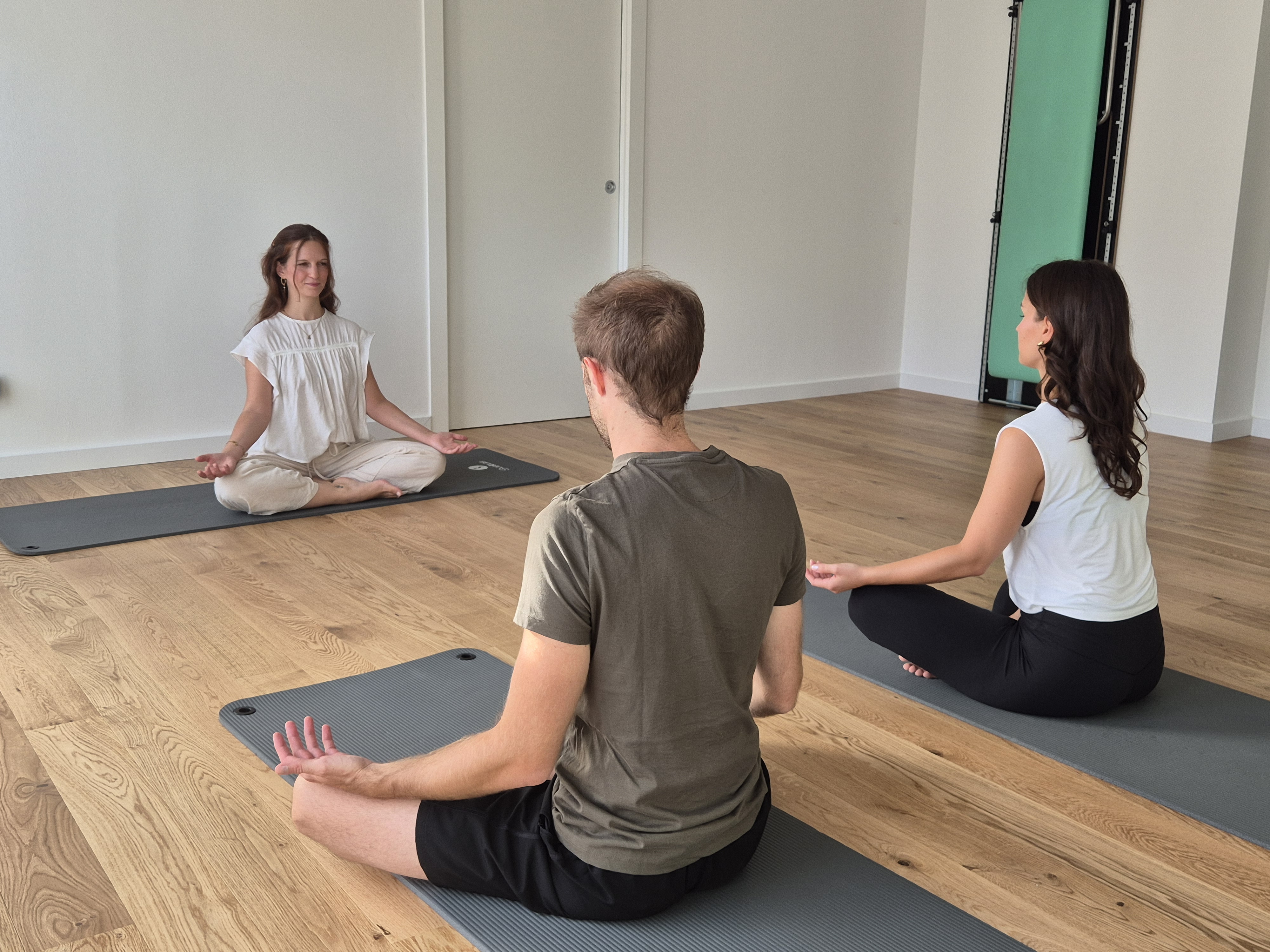 An instructor guiding a client through a Pilates reformer exercise